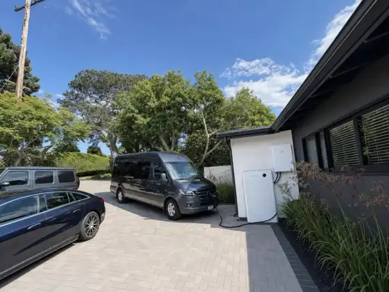 Sigenergy battery system on the side of a home with a van charging
